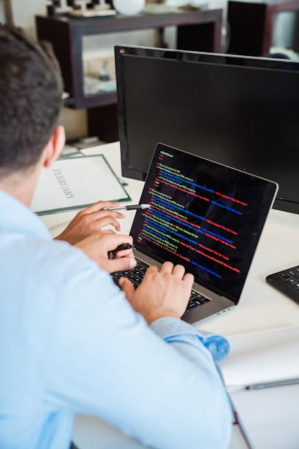 A close-up view of a laptop on a desk, displaying a software development environment with lines of code in an editor window on the left side and a bright orange calculator interface on the right side.